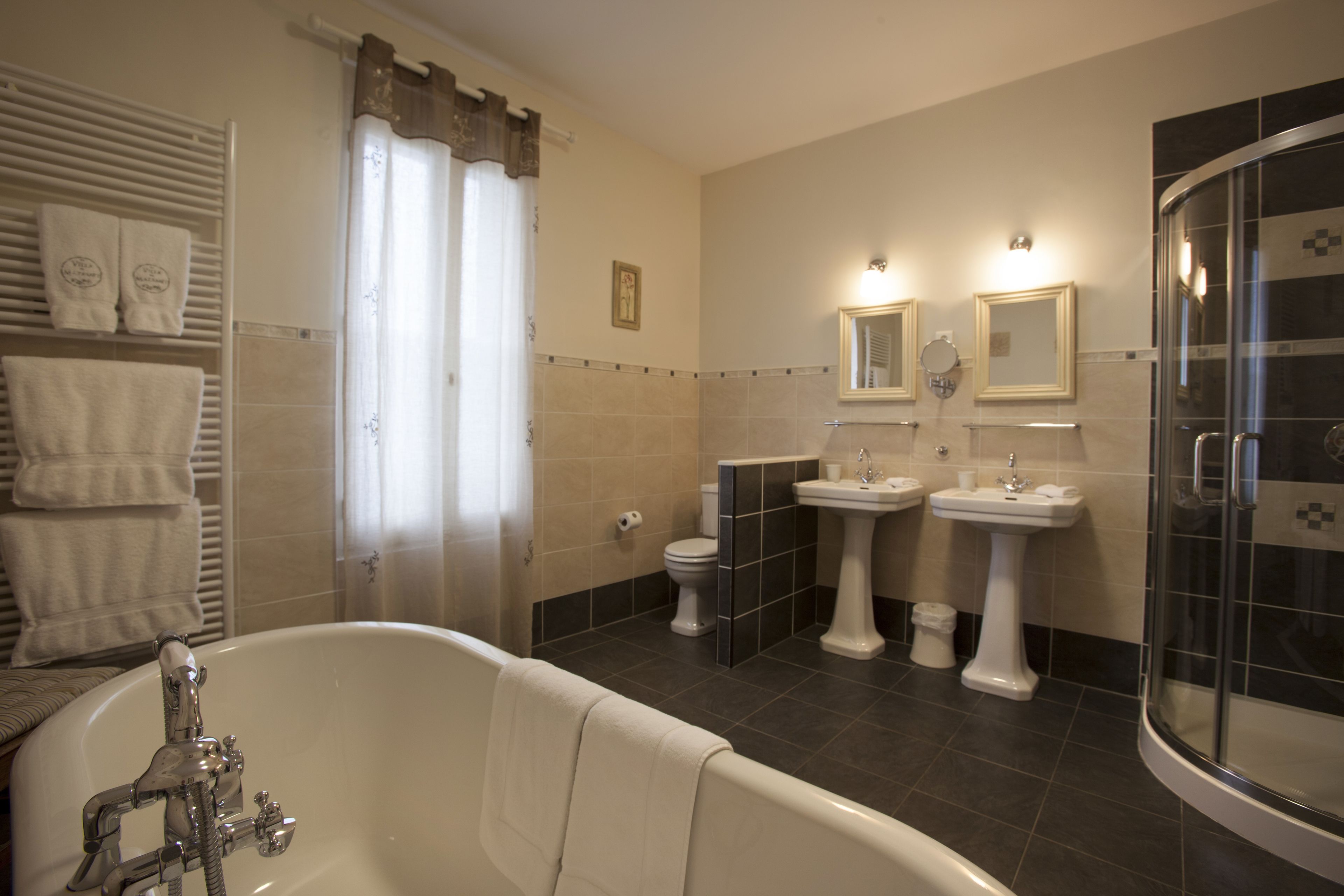 A bathroom with a bathtub, two sinks, a toilet, and a shower enclosure.