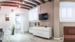 Un salon moderne avec un canapé blanc, un canapé marron, un meuble blanc orné de plantes, un téléviseur à écran plat et un plafond en bois.