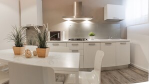 Une cuisine moderne avec des meubles blancs, un îlot central et une hotte de cuisine en acier inoxydable.