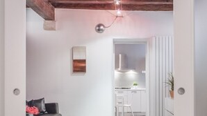 Un intérieur doté d’un plafond en bois, d’un espace cuisine et d’un coin salon avec un canapé et un fauteuil.
