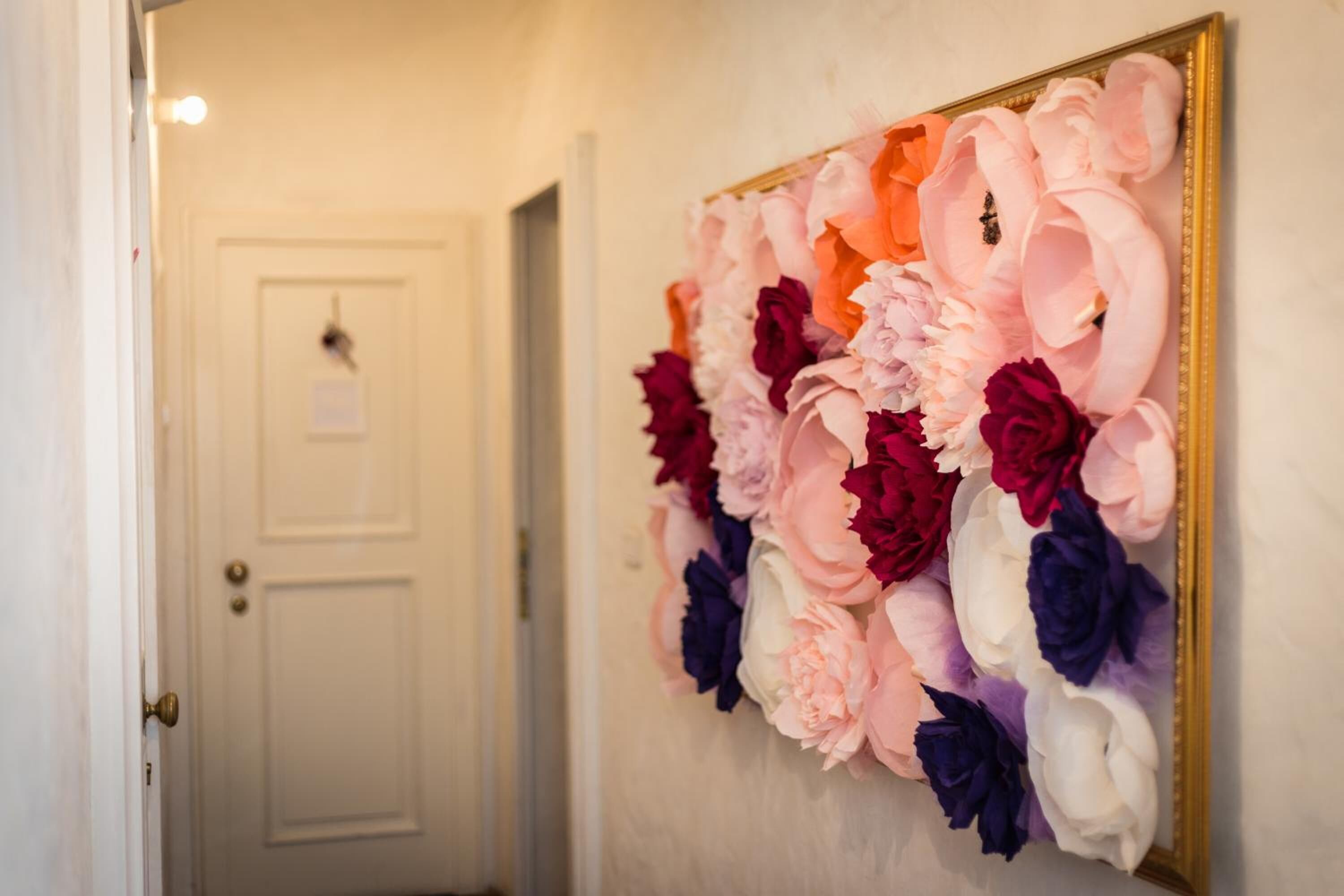 A hallway with a wall-mounted floral arrangement and a closed door.