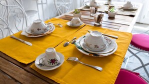 A dining table set with white teacups and saucers, silverware, and a yellow tablecloth. - Antiche Mura (Arezzo)