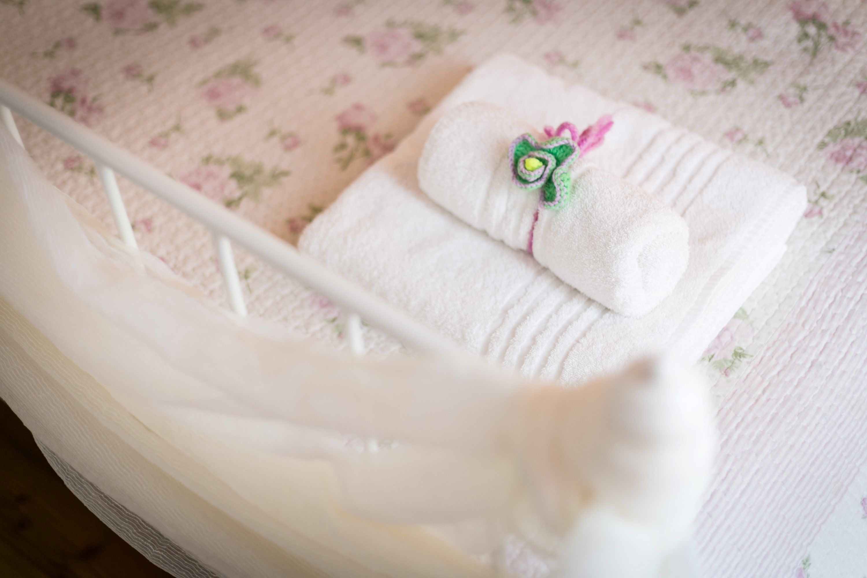 A white crib with a floral-patterned bedspread.