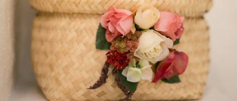 A woven basket with a floral arrangement on a shelf.