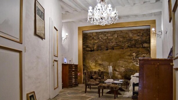 A room with a stone wall, a chandelier, and a wooden cabinet. - Antiche Mura (Arezzo)