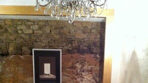 A living room with two armchairs, a sofa, a glass coffee table, and a stone wall. - Antiche Mura (Arezzo)