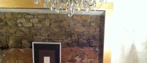 A living room with two armchairs, a sofa, a glass coffee table, and a stone wall.