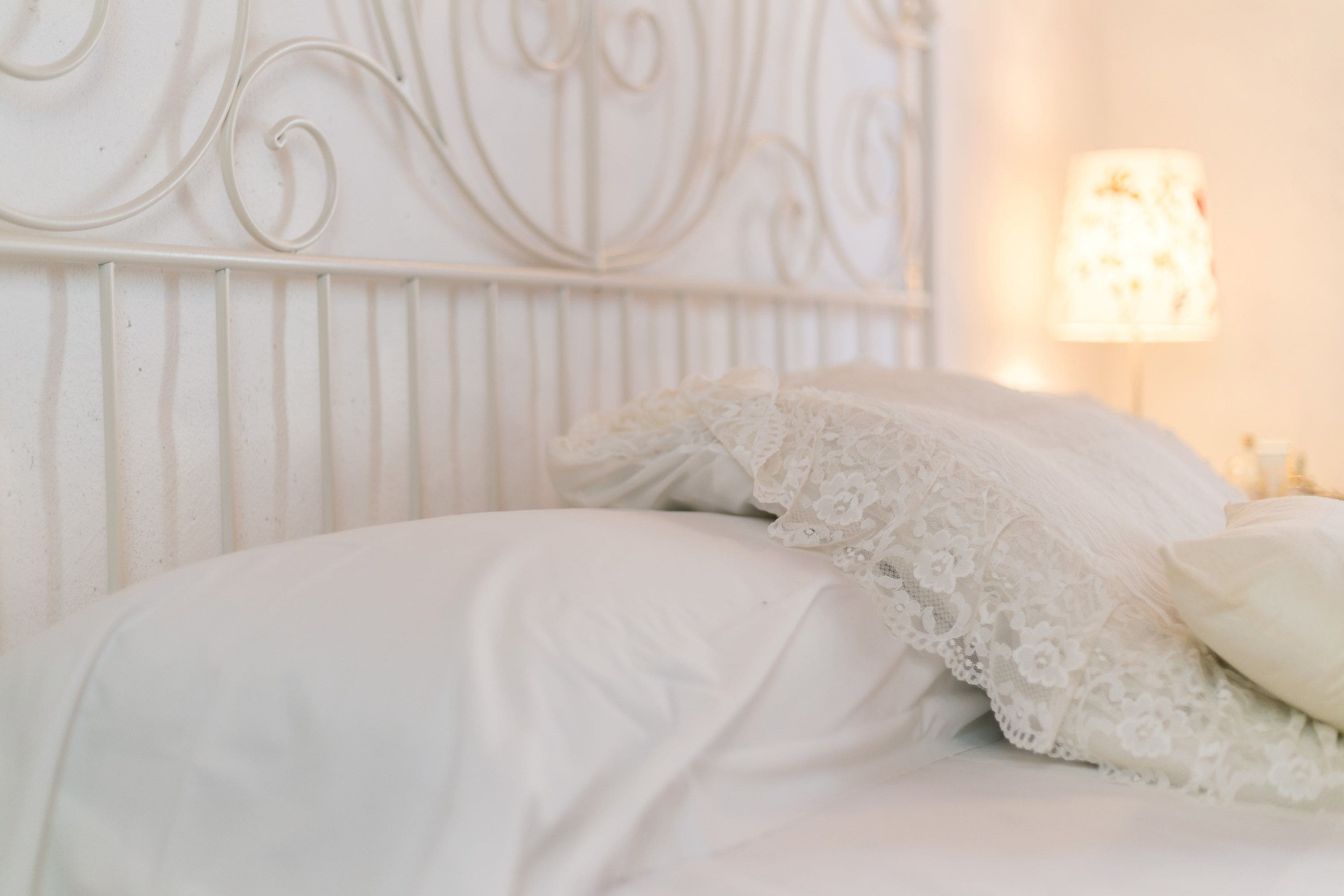 Ein Bett mit weißen Laken und einem dekorativen Kopfteil.