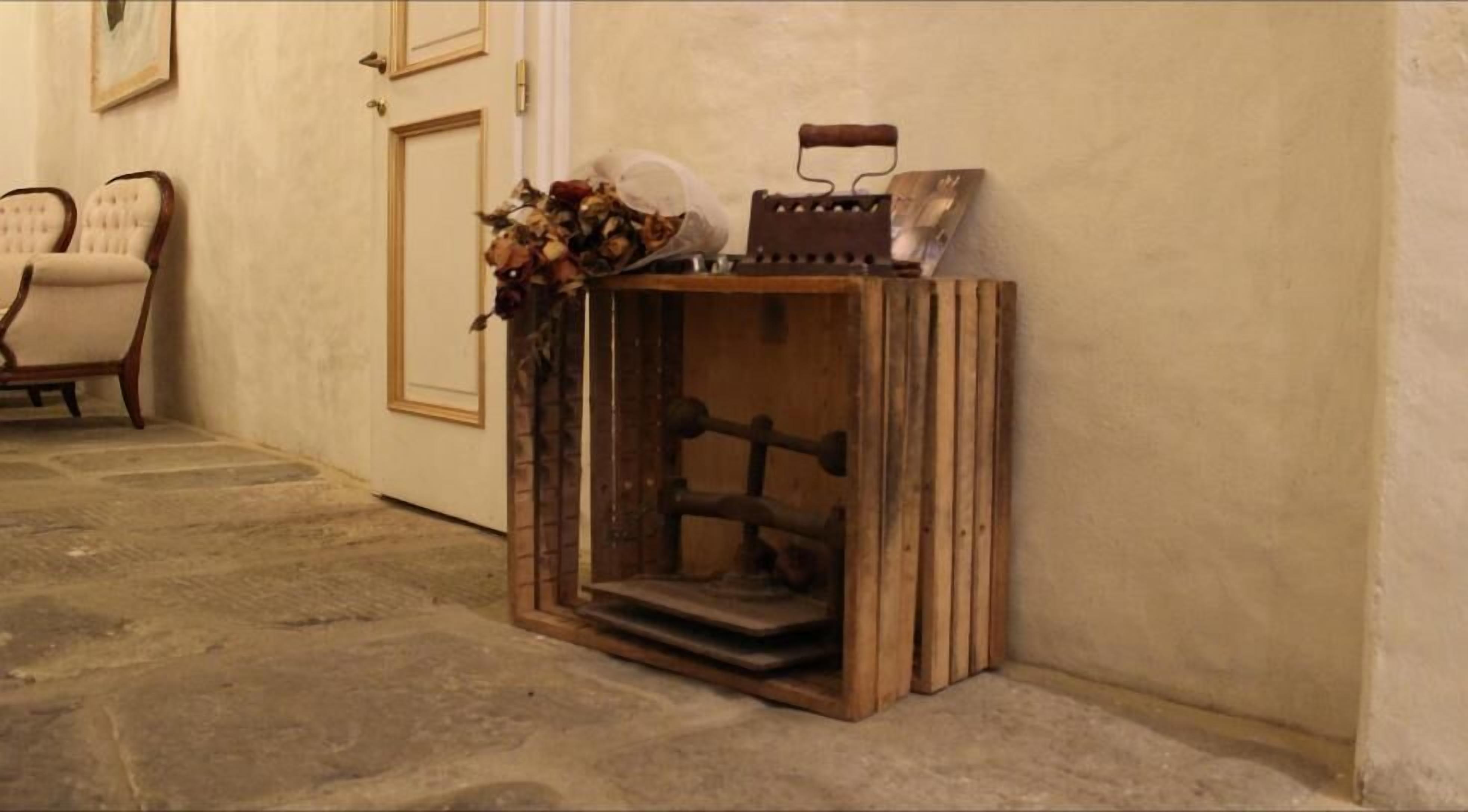 Un racó amb un armari de fusta adossat a la paret, una cadira i una porta.