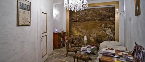 A room with a stone wall, a chandelier, a wooden cabinet, and a sofa.