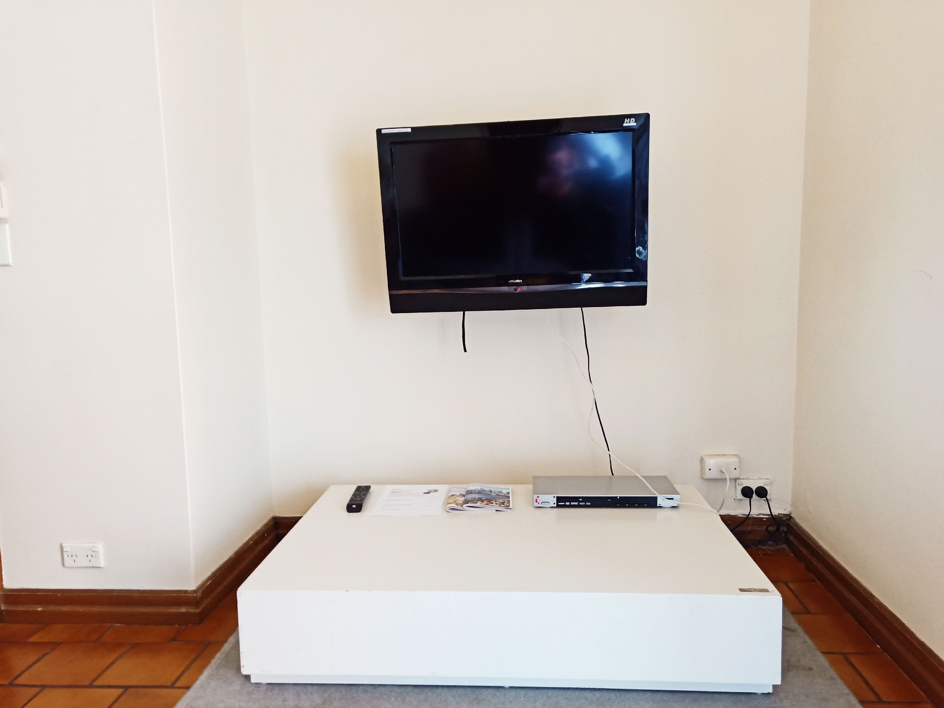 A white entertainment unit with a flat-screen TV mounted above it.