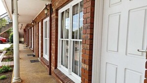 A brick building with white-framed windows and a white door. - Glen Inn (Glen Waverley)