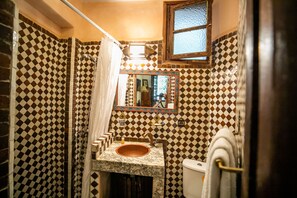 Tweepersoonskamer | Badkamer | Een douche, een haardroger, handdoeken, zeep