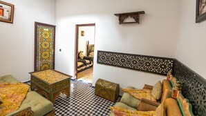 A room with a checkered floor, a sofa set, a decorative cabinet, and a bed with a headboard. - Riad Jardin Chrifa (Fes)