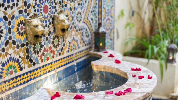 A traditional Moroccan fountain with a mosaic wall and a marble basin. - Riad Jardin Chrifa (Fes)