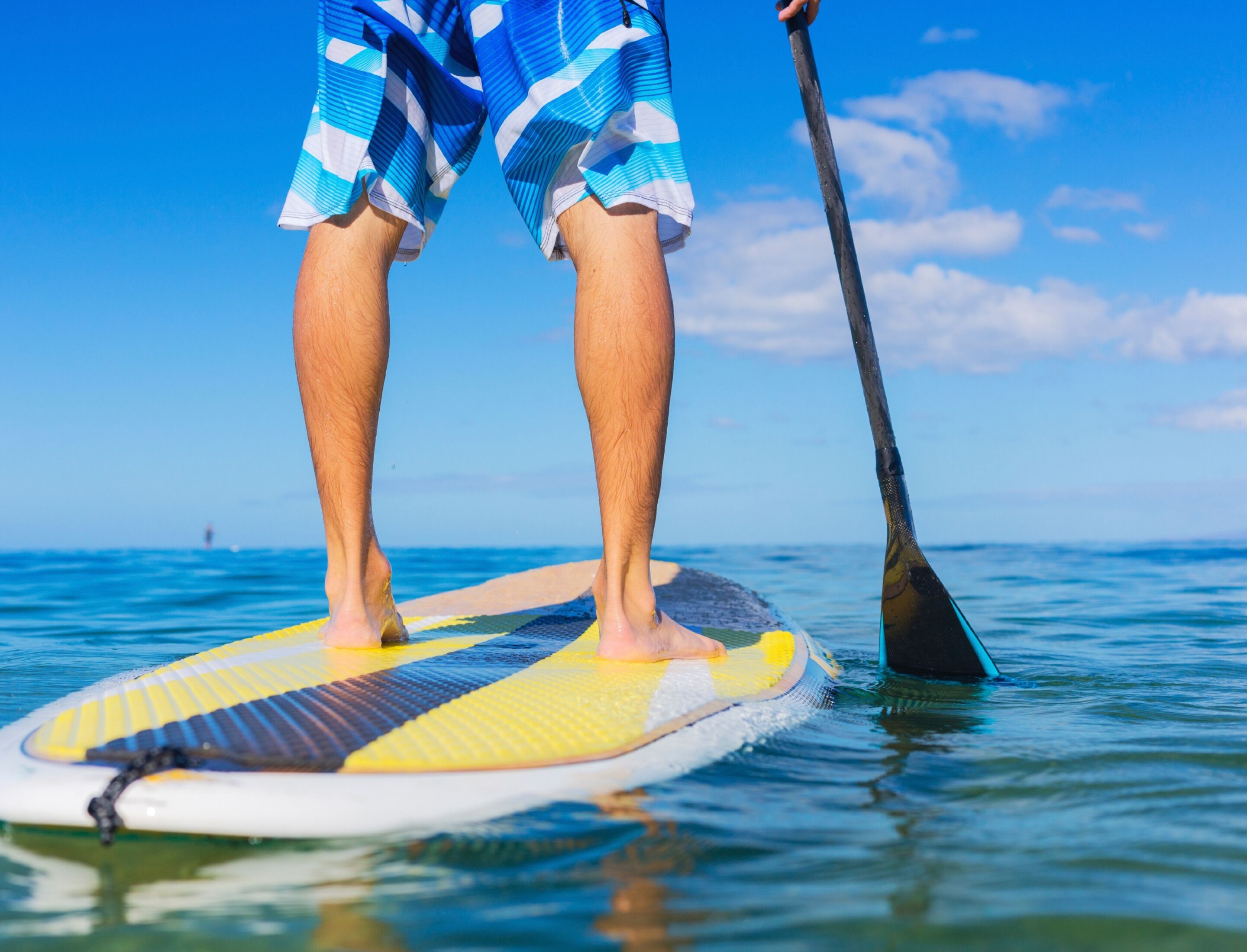 A person standing on a paddleboard in the water.