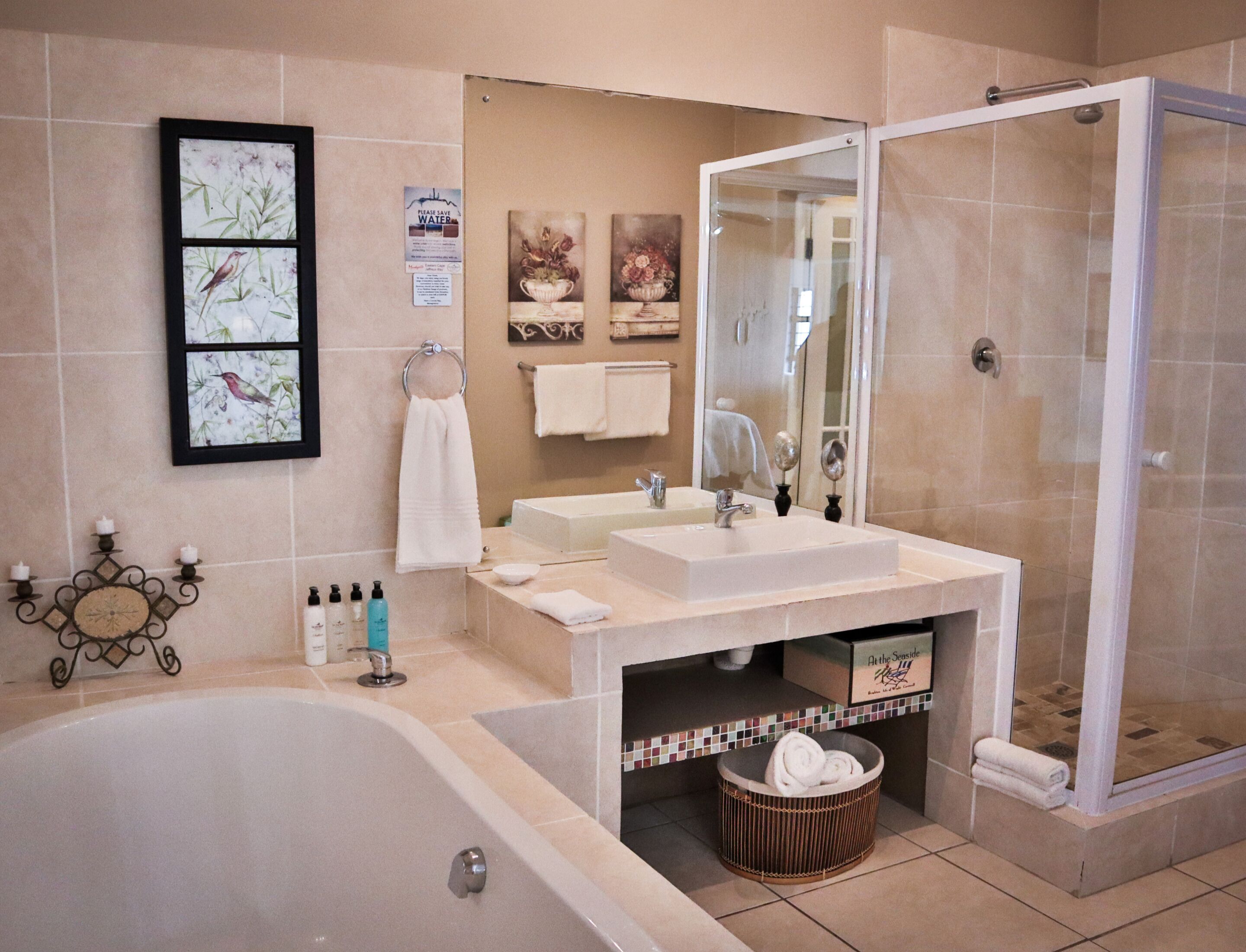 A modern bathroom with a bathtub, a shower, a sink, and a mirror. There are towels and toiletries on the counter.