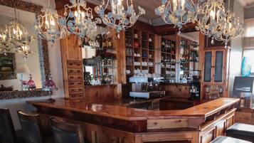 Uma área de bar com móveis de madeira, uma máquina de café e lustres decorativos.