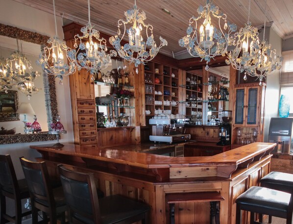 A bar area with wooden furniture, a coffee machine, and decorative chandeliers. - On the Beach Guesthouse (Jeffreys Bay)