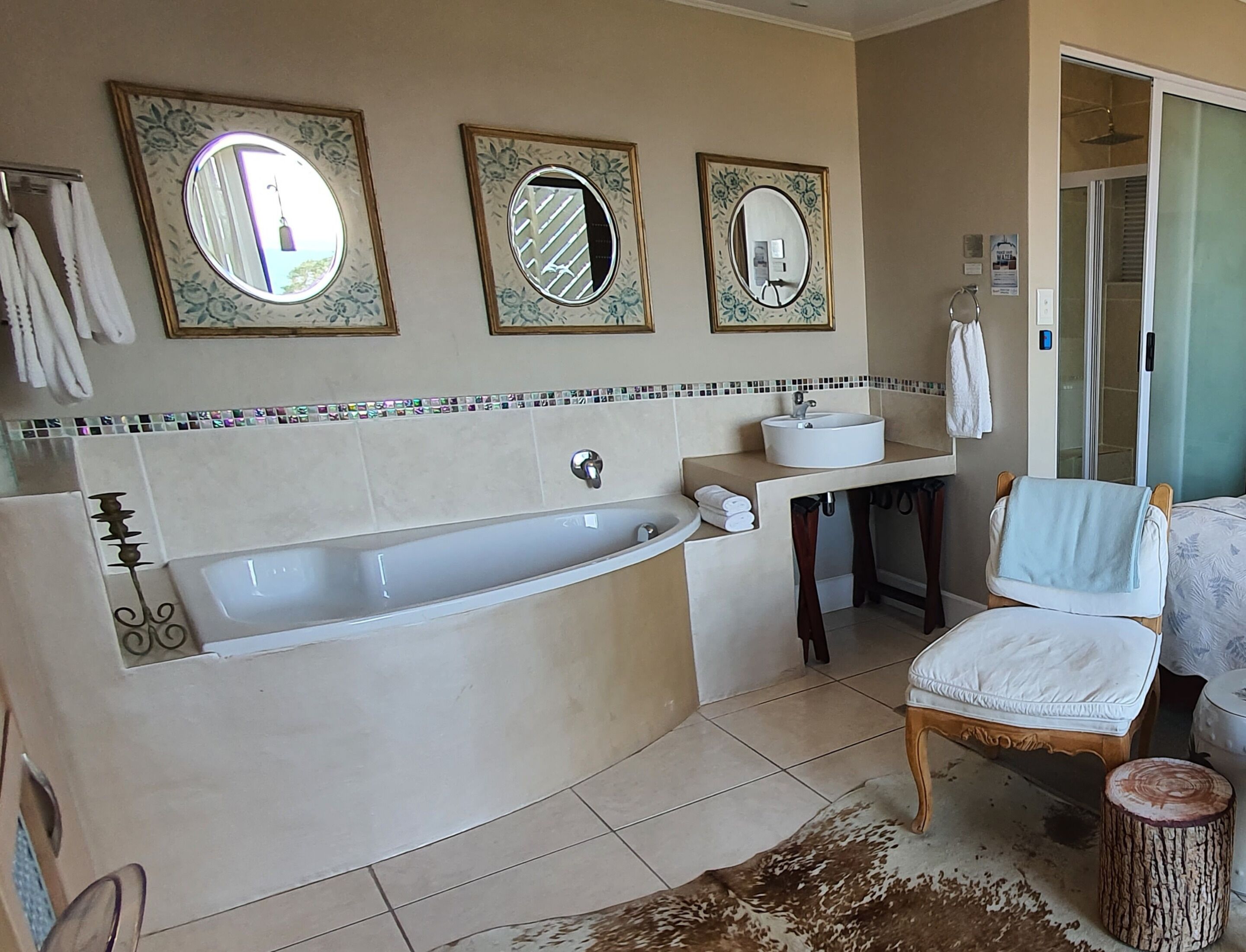 A bathroom with a bathtub, two sinks, and three mirrors.