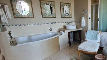 A bathroom with a bathtub, two sinks, and three mirrors.