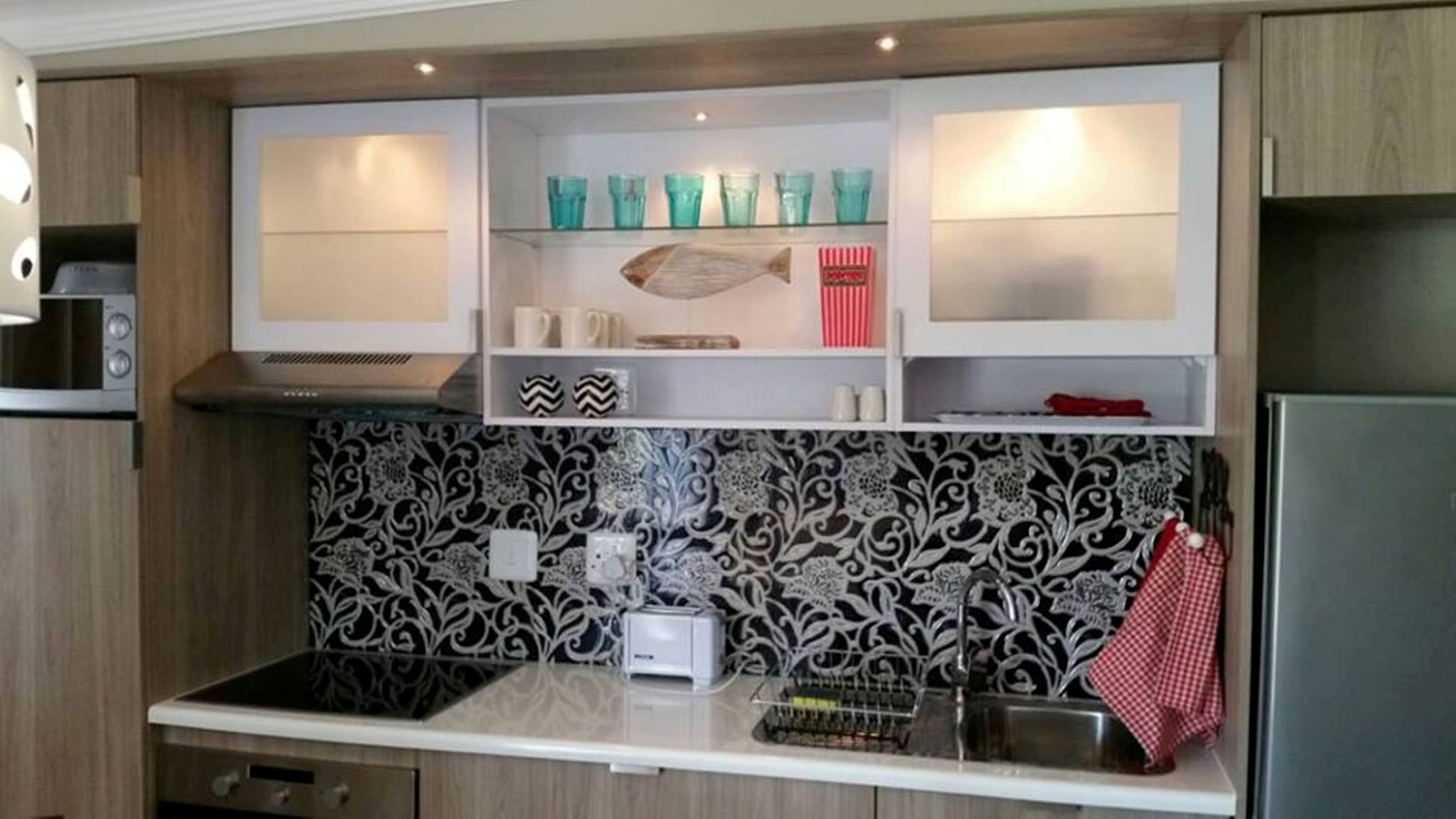 A compact kitchen with a microwave, toaster, and a sink.