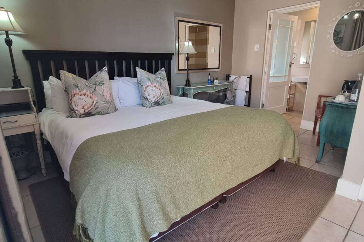 Une chambre à coucher bien rangée, avec un lit, des lampes de chevet, une commode et un miroir.