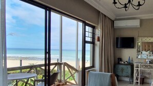 Quarto de hotel com uma varanda grande, uma cama, uma televisão e um penteoureiro.