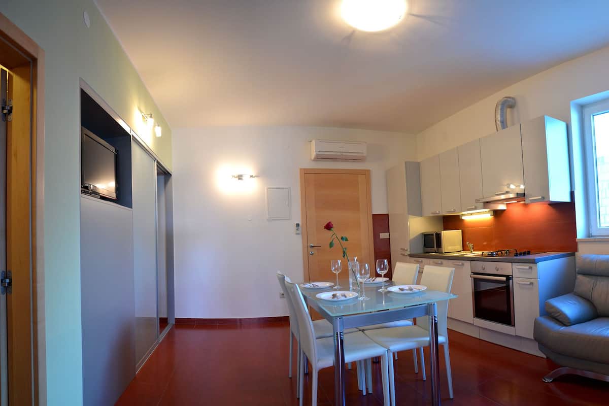 A compact living space with a dining area, kitchenette, and a seating area with a sofa.