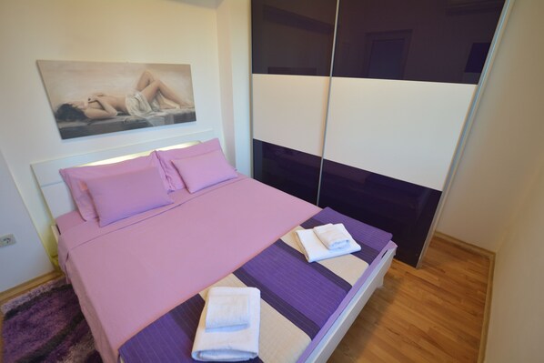 Quarto com cama, almofadas, um quadro na parede e um espelho.