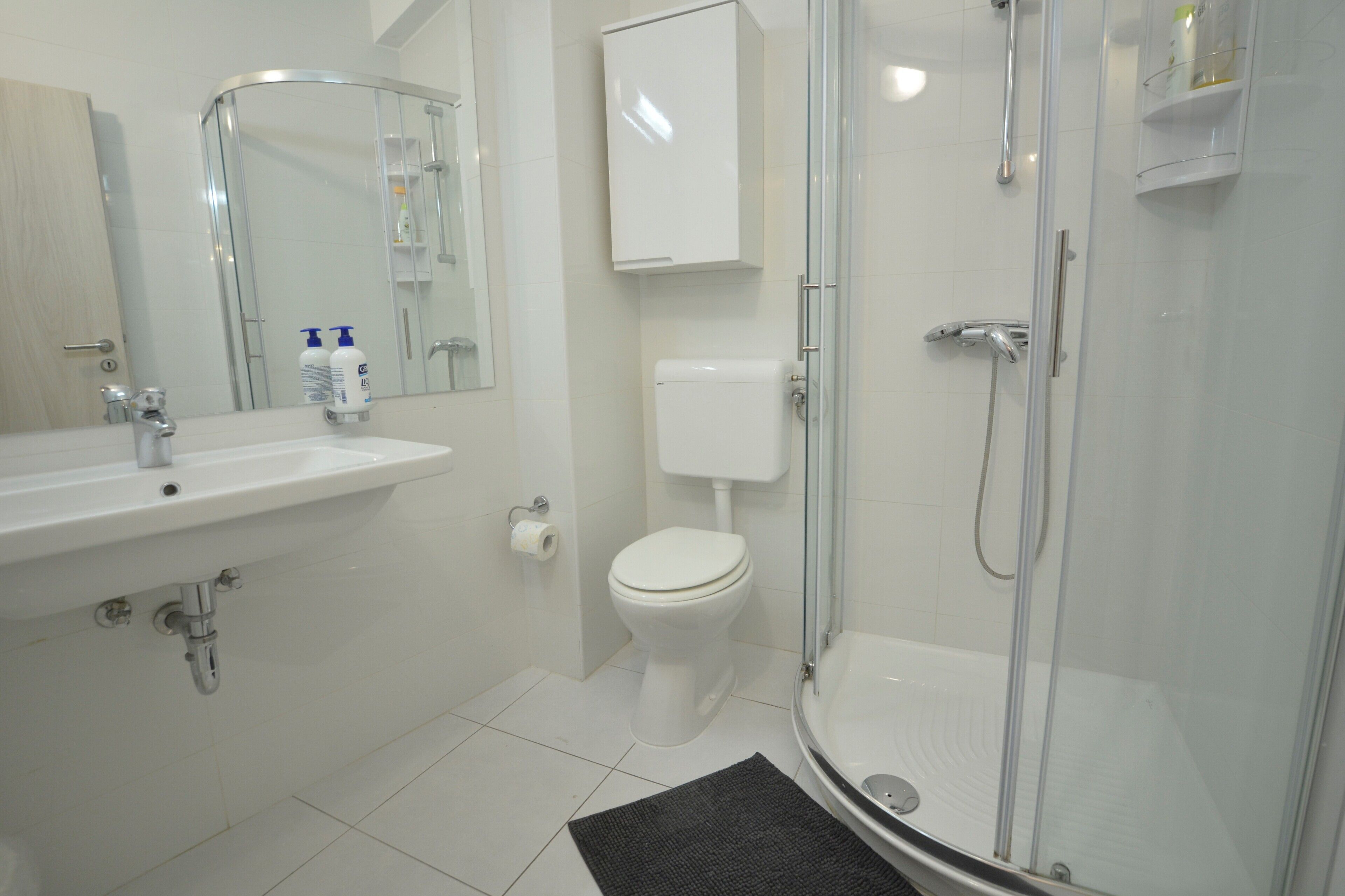 Une salle de bain moderne avec un lavabo, des toilettes et une douche à parois de verre.