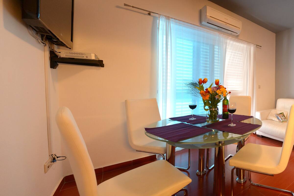 A dining area with a glass table, white chairs, and a white sofa.
