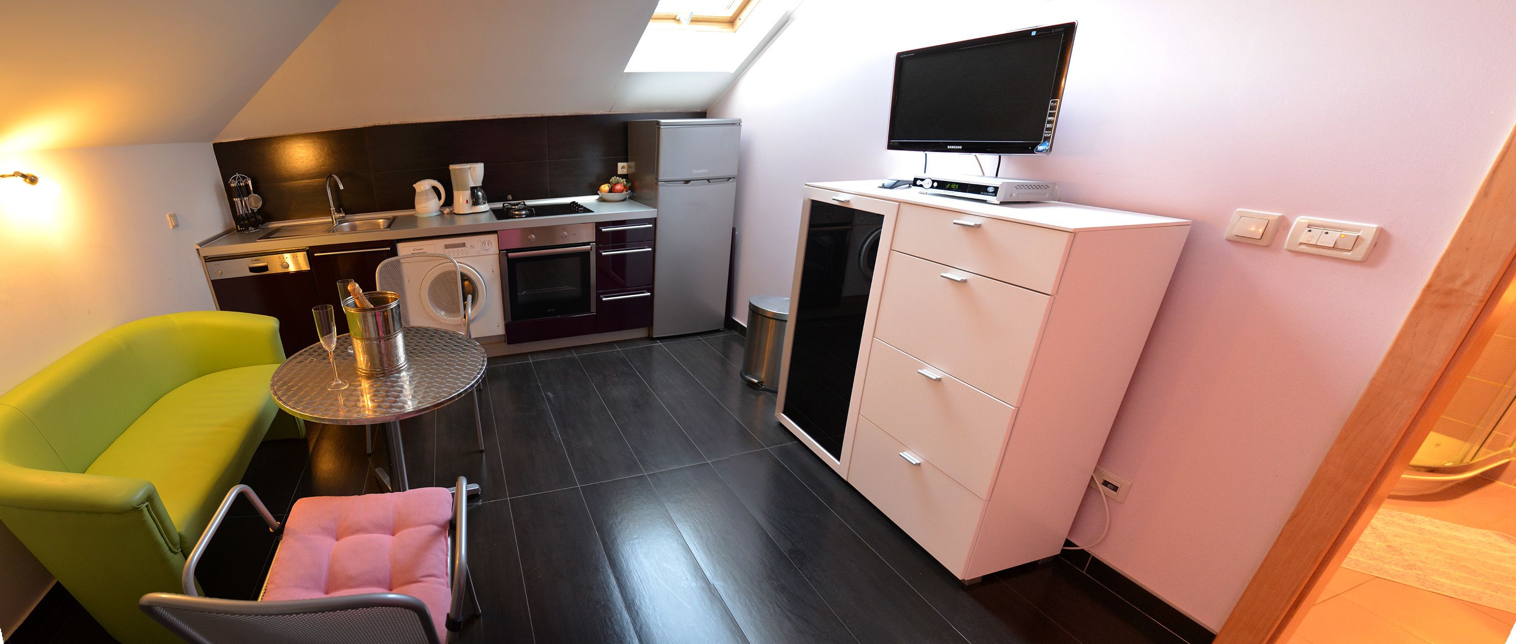 Een compacte keuken met een wasmachine, een eettafeltje en een stoel.