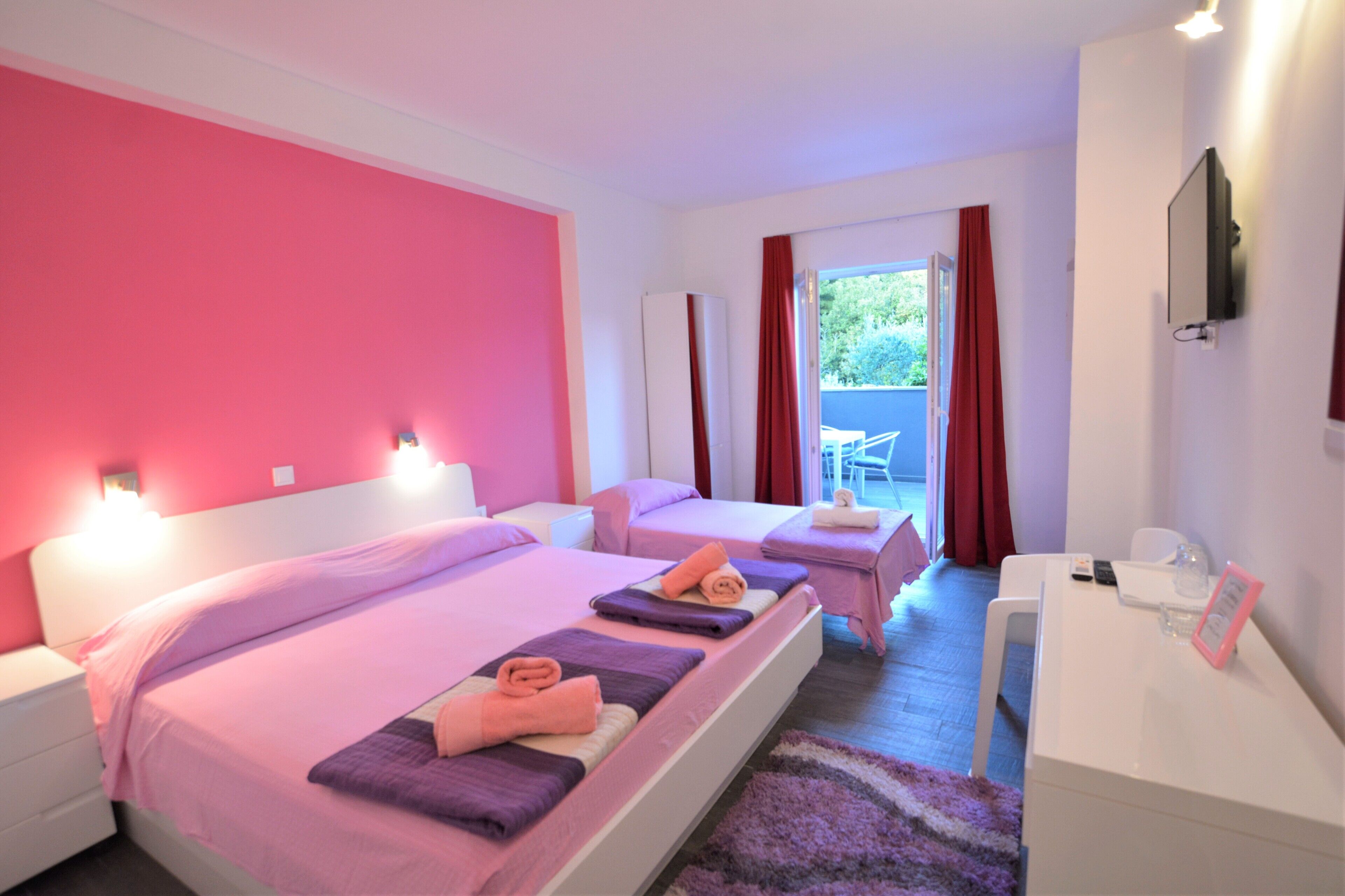 Quarto de hotel com duas camas, uma escrivaninha e televisão.