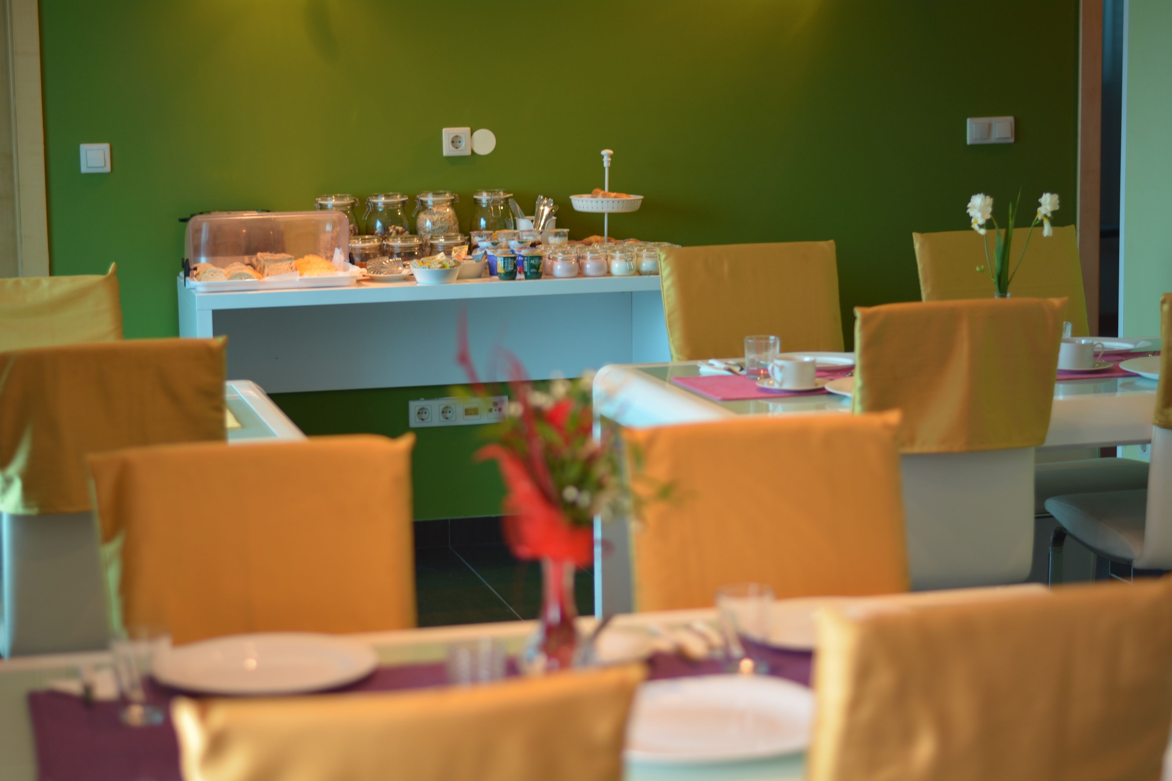 A dining area with tables set for service, a buffet counter with various food items, and chairs with yellow cushions.