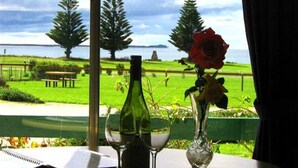 Une table avec un carnet, une bouteille de vin et un vase contenant une rose.