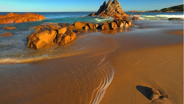 Une plage avec de gros rochers et des vagues.