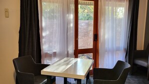 Una stanza con un tavolo e due sedie, una porta che dà sull'esterno e un pavimento con tappeto.