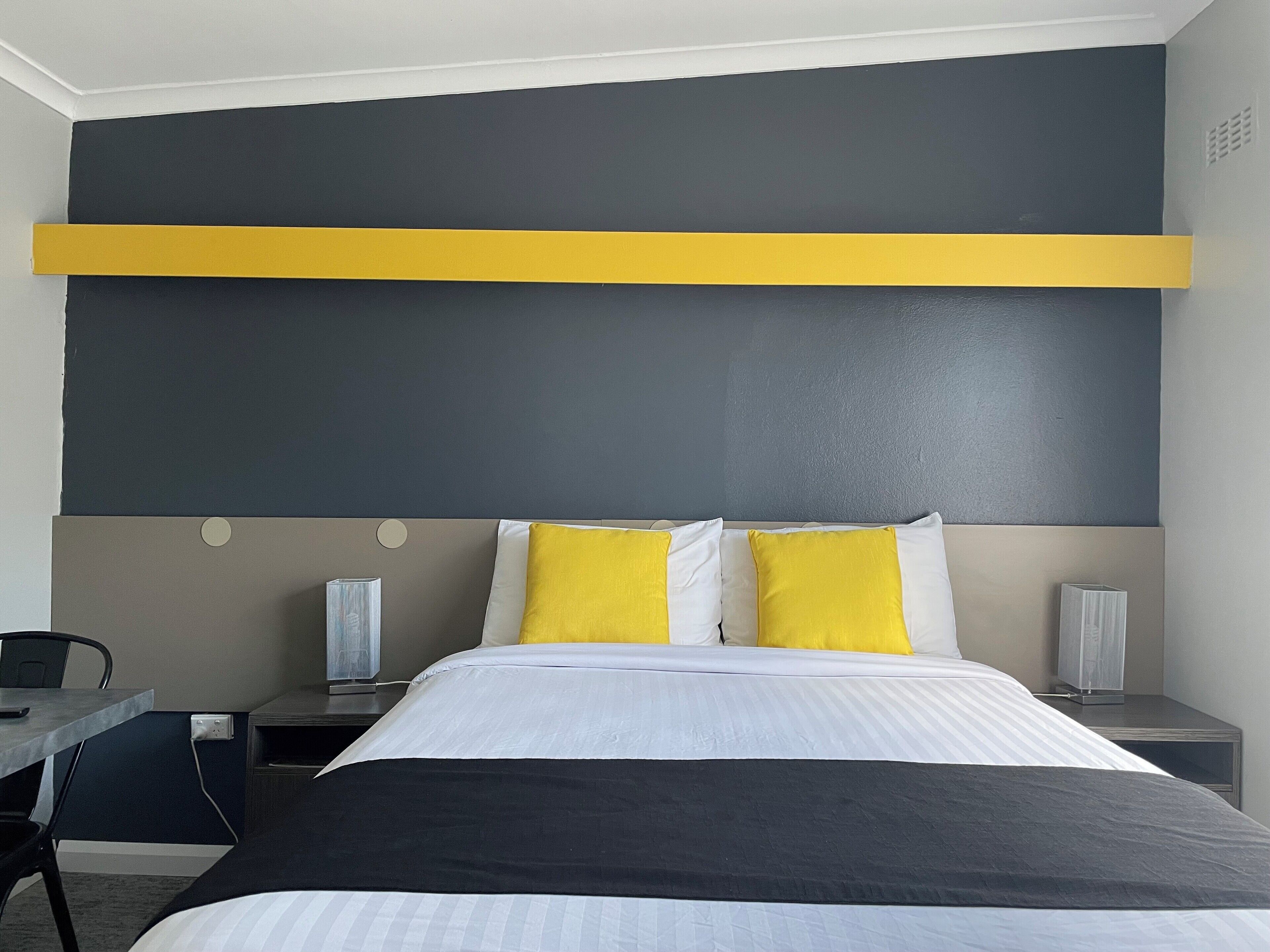 A modern hotel room with a large bed, two bedside tables, a desk, and a chair.