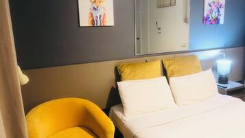 Ein Hotelzimmer mit Bett, zwei Kissen, einem Nachttisch mit Lampe und zwei an der Wand hängenden Bildern.