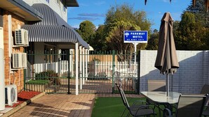 Esterno di un hotel con patio lastricato, posti a sedere all'aperto e insegna del Parkway Motel.