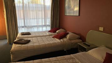A hotel room with two beds, a nightstand, a painting on the wall, and a window with curtains.