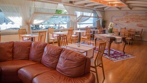 A restaurant with wooden furniture, large windows, and a mural on the wall. - Hotel Aquadolce (Verbania)