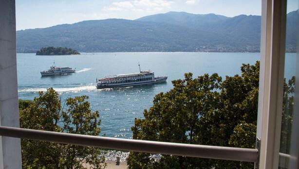 A view of a lake with boats, a distant island, and mountains in the background. - Hotel Aquadolce (Verbania)