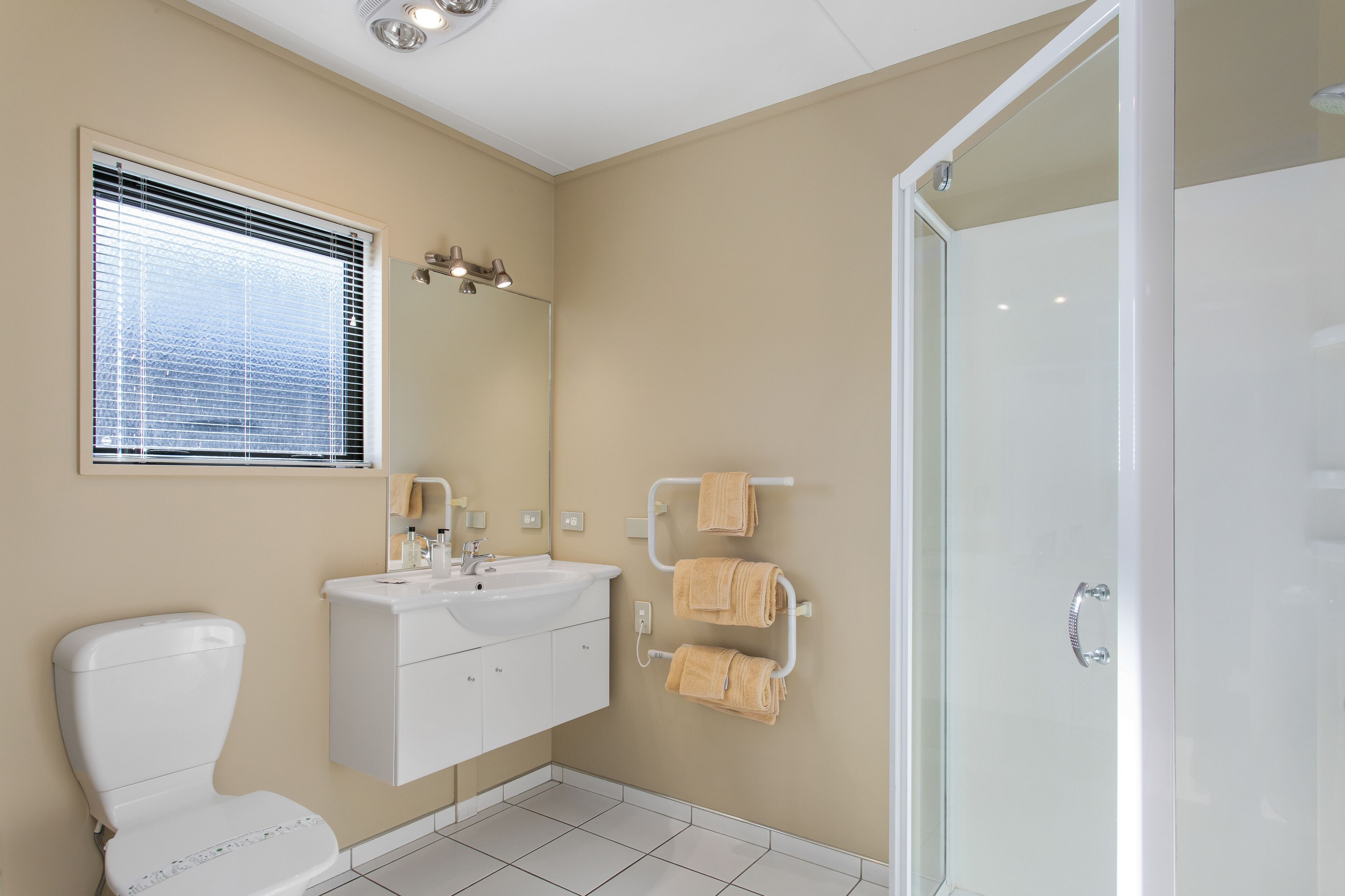 A modern bathroom with a toilet, sink, and glass shower enclosure.