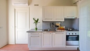 A modern kitchen with white cabinets, a stainless steel sink, and an oven. - Casali Romei - Apartments (Sarzana)