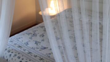 A bed with a floral-patterned mattress, a white canopy, and a bedside lamp.