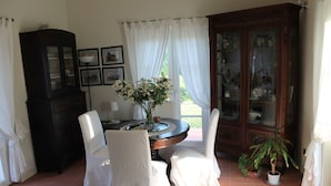 A dining area with a round table, two chairs, a cabinet, and a potted plant. - Casali Romei - Apartments (Sarzana)
