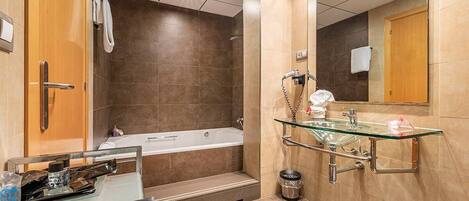 Un baño moderno con un lavabo con cerramiento de vidrio, una bañera y una zona de ducha.