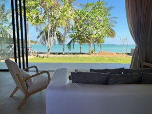 A bedroom with a large bed, a chair, and a view of the beach and ocean. - Samui Garden Home (Koh Samui)